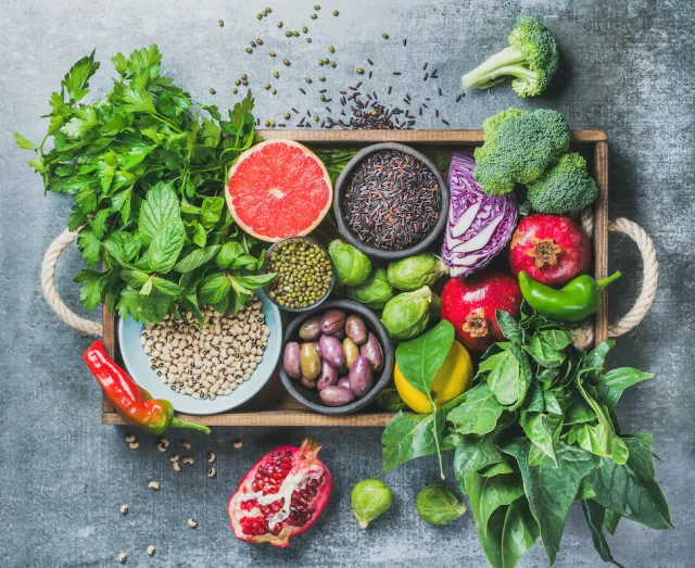 A wooden tray of fresh vegetables, herbs, fruit, grains and legumes